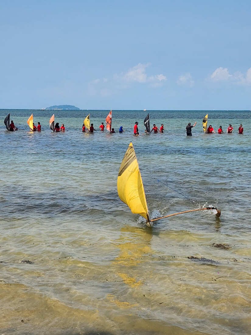 Kids in red uniforms lined up in the shallows with their jongs